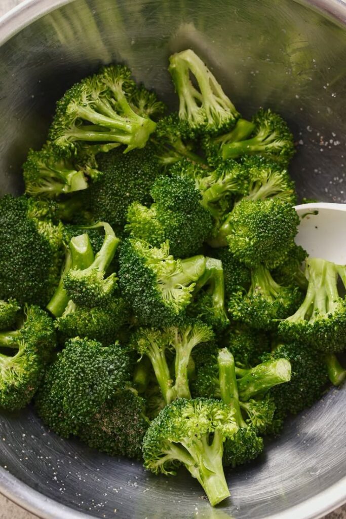 Fresh, steamed broccoli florets in stainless steel bowl, ready for a healthy meal preparation.