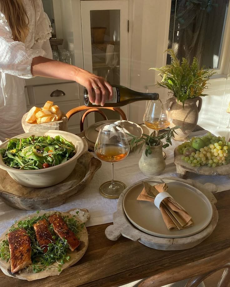 A cozy dinner setting with salad, roasted salmon, wine, and bread, highlighting a warm, inviting atmosphere.
