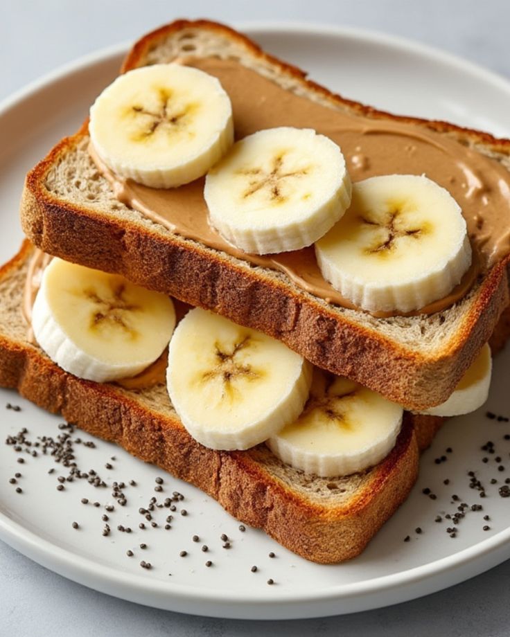 Whole grain toast with peanut butter, banana slices, and chia seeds on a plate, perfect for a healthy breakfast.