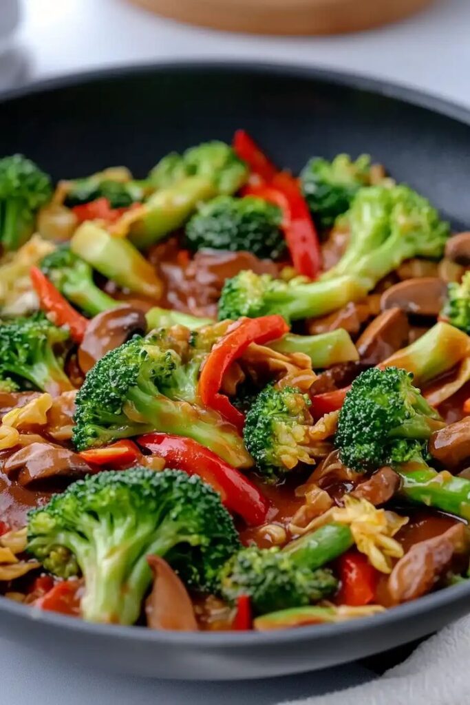 Delicious stir-fried broccoli and bell peppers with mushrooms in a black pan, perfect for a healthy meal.