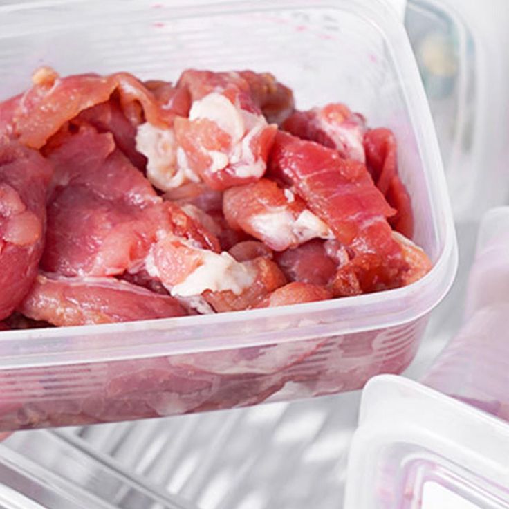 Raw meat stored in a clear plastic container, refrigerated for freshness.