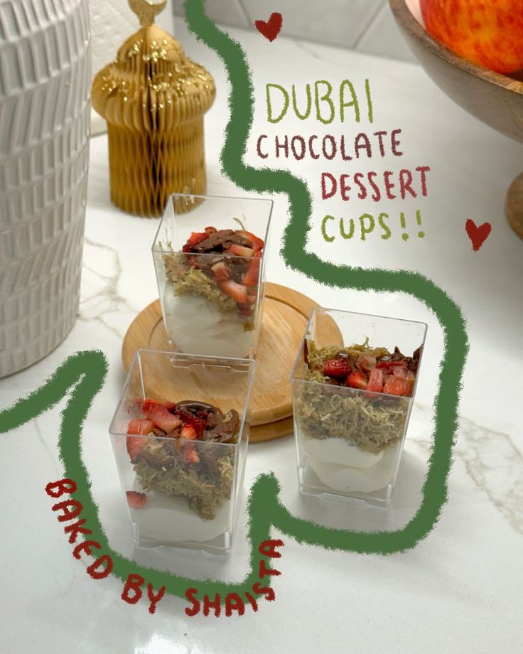 Three glass cups with Dubai chocolate dessert topped with strawberries on a wooden tray. Text: Baked by Shaista.