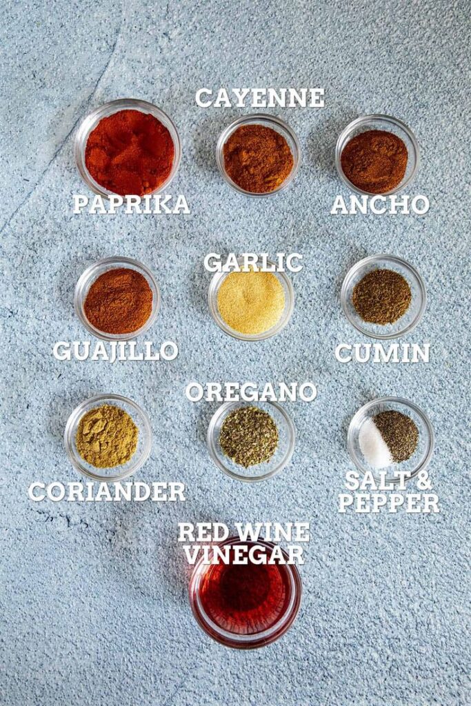 Nine glass bowls with paprika, cayenne, ancho, guajillo, garlic, cumin, coriander, oregano, and red wine vinegar.
