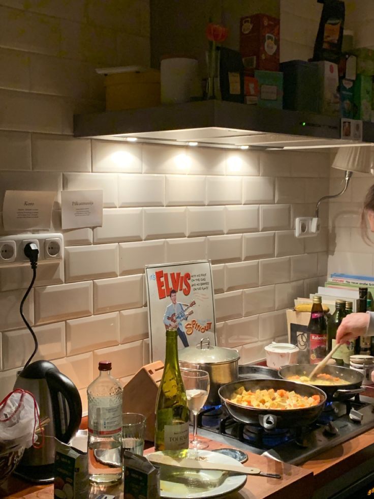 A cozy kitchen scene with cooking, wine, and a vintage Elvis poster by the tiled backsplash.