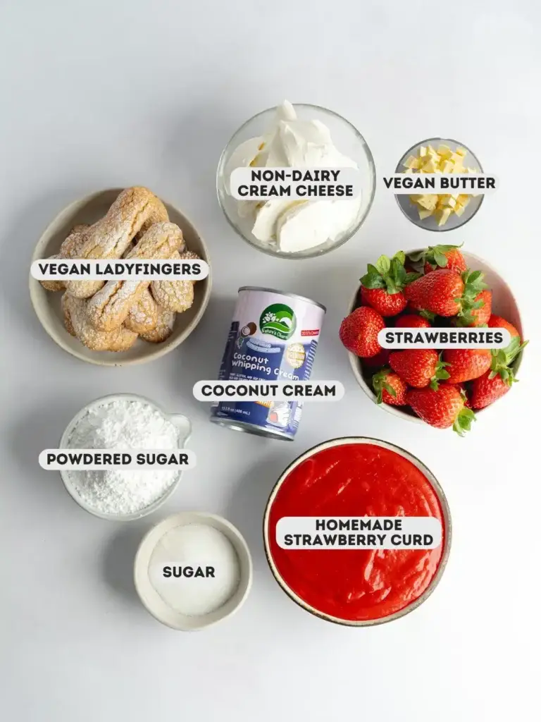 Assorted vegan dessert ingredients including strawberries, non-dairy cream cheese, and coconut cream on white background.