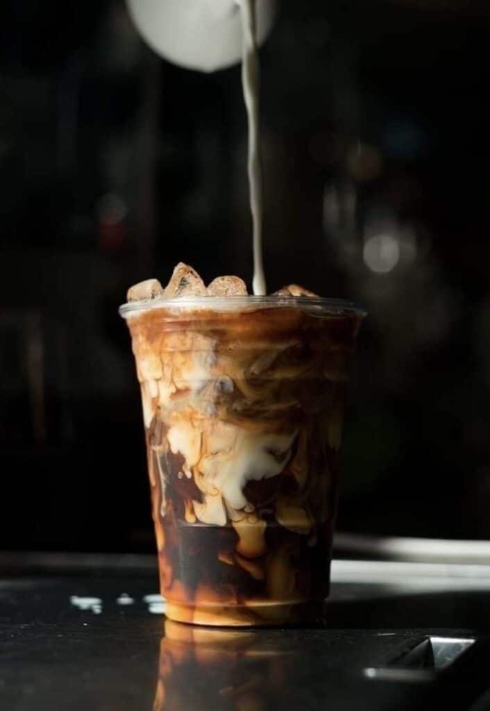 Iced coffee with cream swirling in a clear cup, capturing the perfect caffeinated refreshment moment.