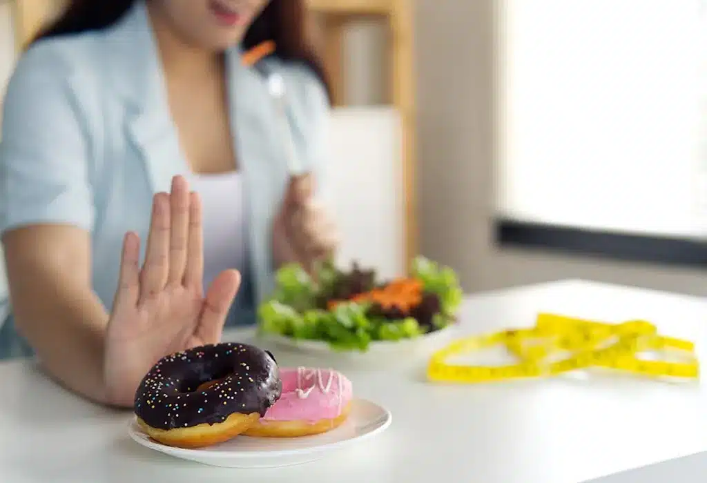 Person choosing salad over donuts, symbolizing healthy eating and weight management with a measuring tape in the background.