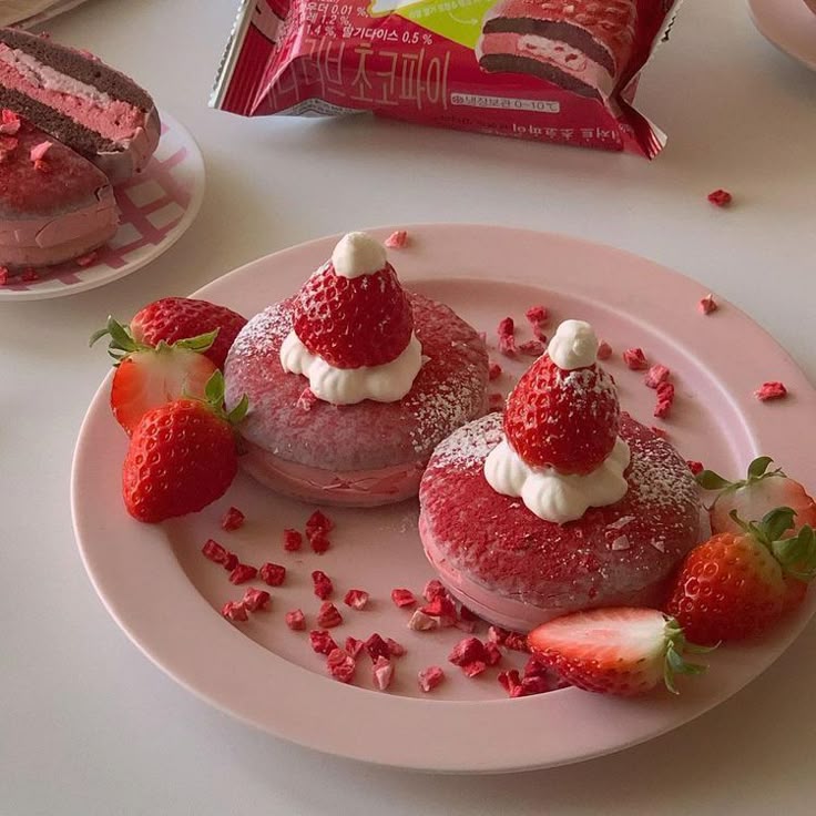 Festive strawberry macarons topped with whipped cream on a pink plate, surrounded by fresh strawberries.