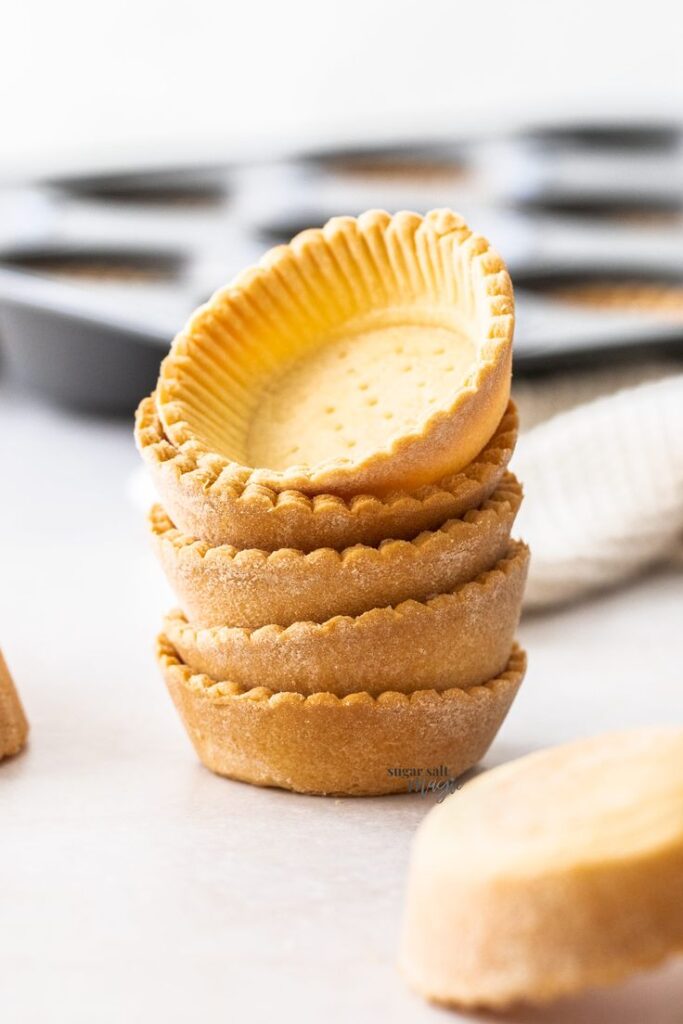 Stack of empty pie crusts ready for filling, in a light kitchen setting. Perfect for baking seasonal tarts.