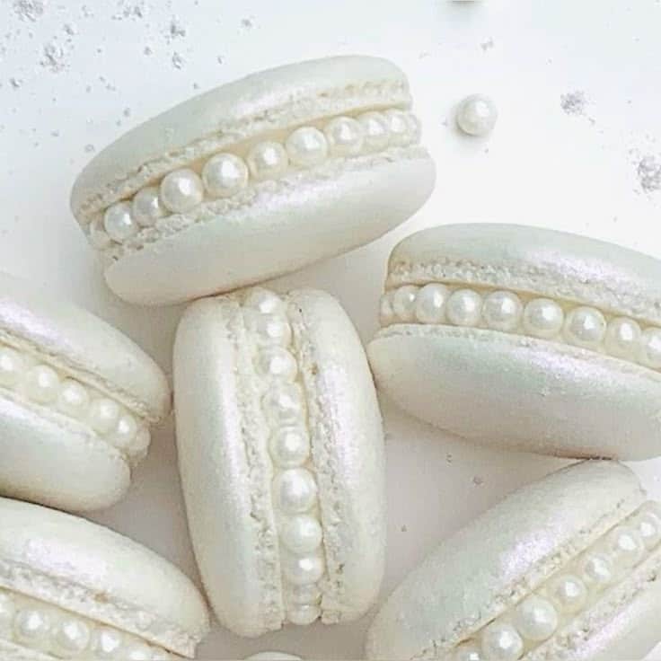 Elegant white macarons with pearl decorations, perfect for weddings or special occasions.