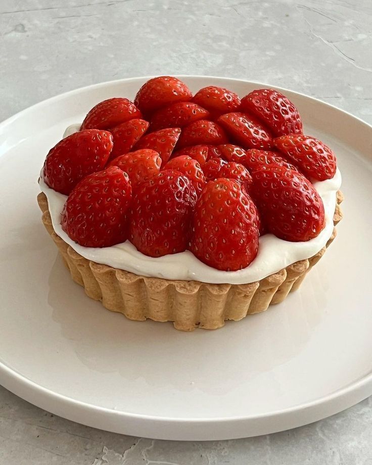 Strawberry tart with creamy filling on a white plate, perfect dessert for summer.