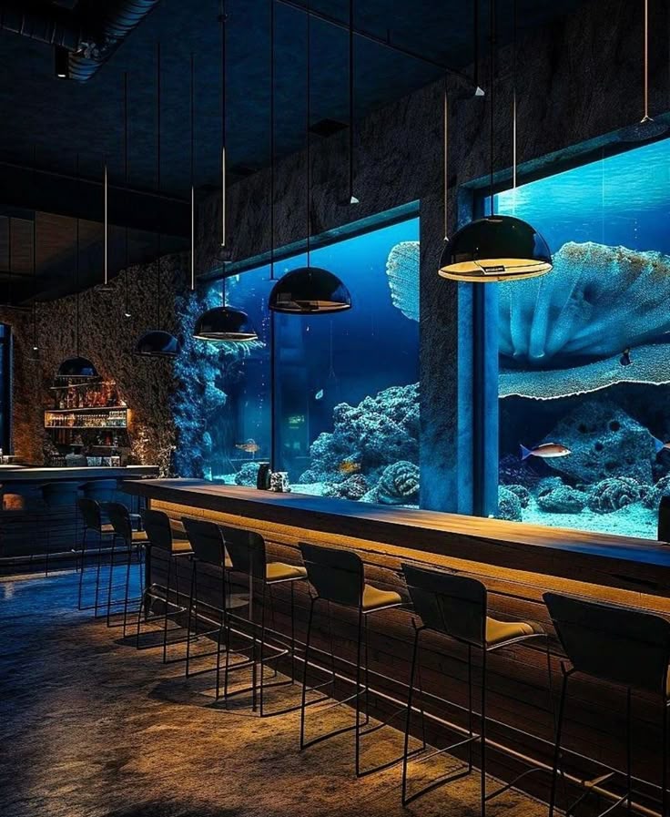 Underwater-themed bar with aquarium view, showcasing a vibrant coral reef and stools for seating.