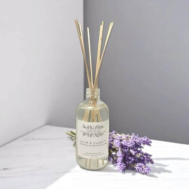 Reed diffuser labeled Calm & Clarity with lavender flowers on a marble surface.