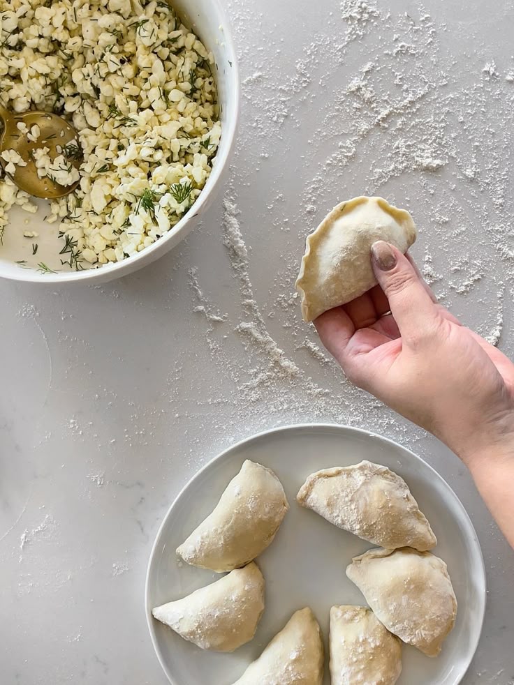 Hand making dumplings with cheese filling on a floured surface, ready for cooking.