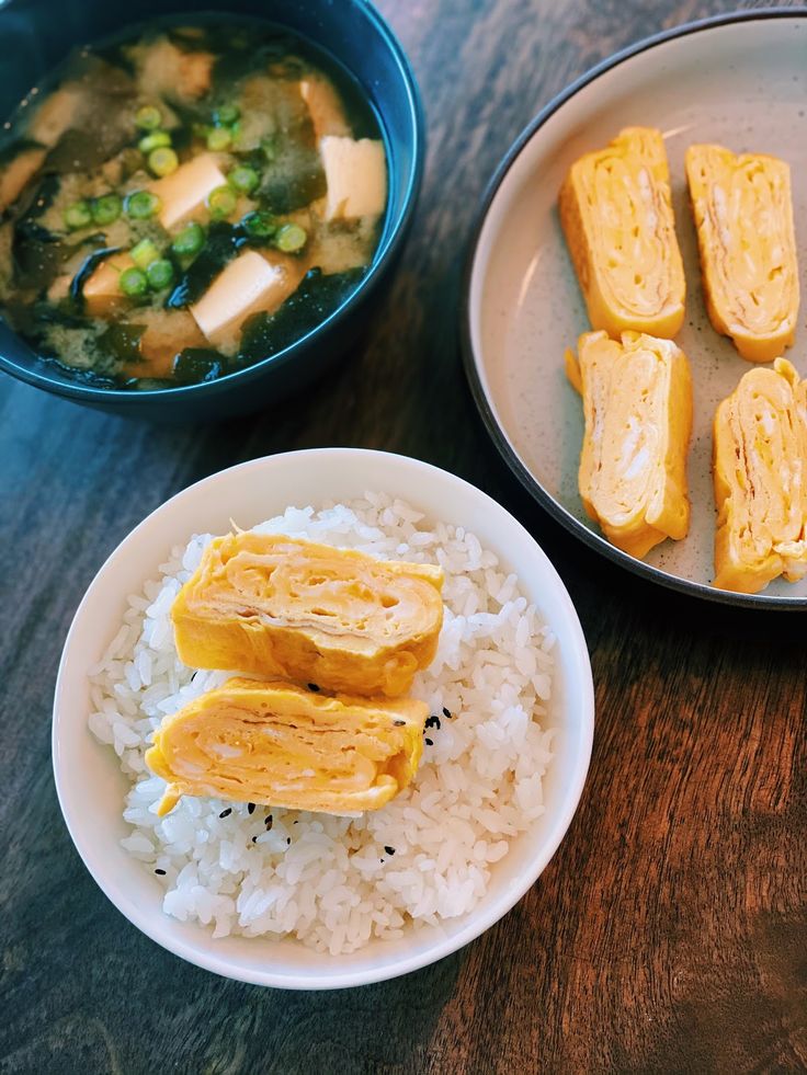 Japanese tamagoyaki on rice with miso soup, showcasing a traditional breakfast on a wooden table.