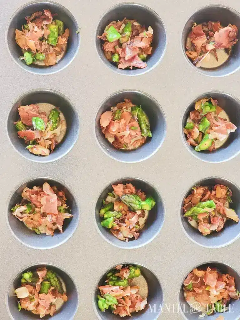 Muffin tin filled with prosciutto and asparagus mixture, ready for baking.
