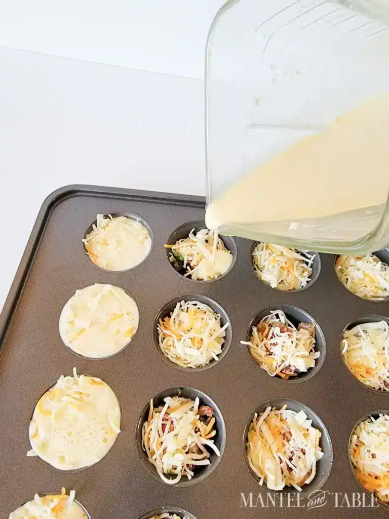 Pouring egg mixture into muffin tins with cheese and vegetables for homemade mini quiches.