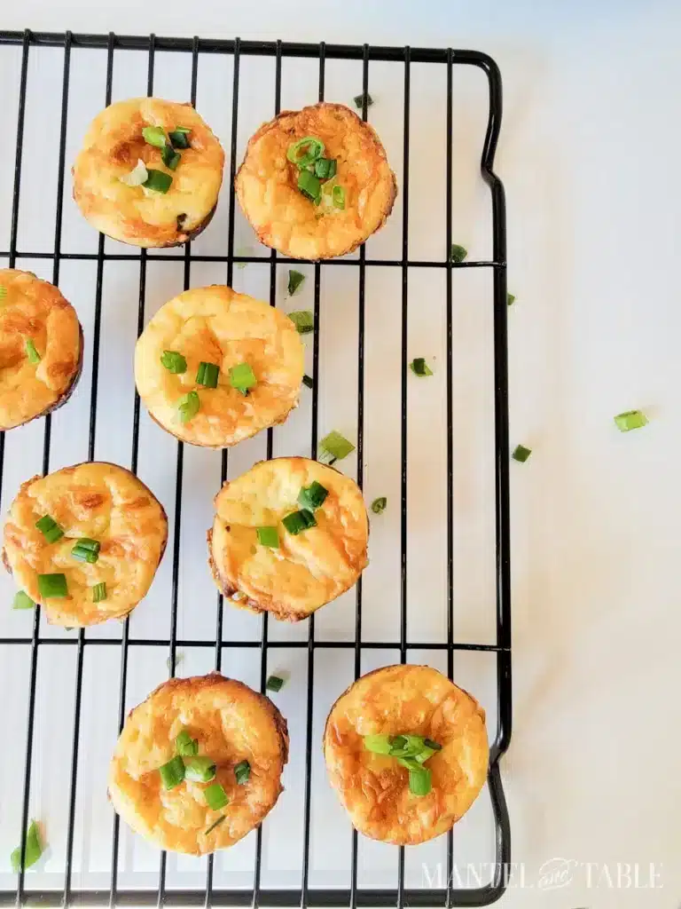 Mini cheese quiches with green onions on a cooling rack, perfect for brunch or appetizers.