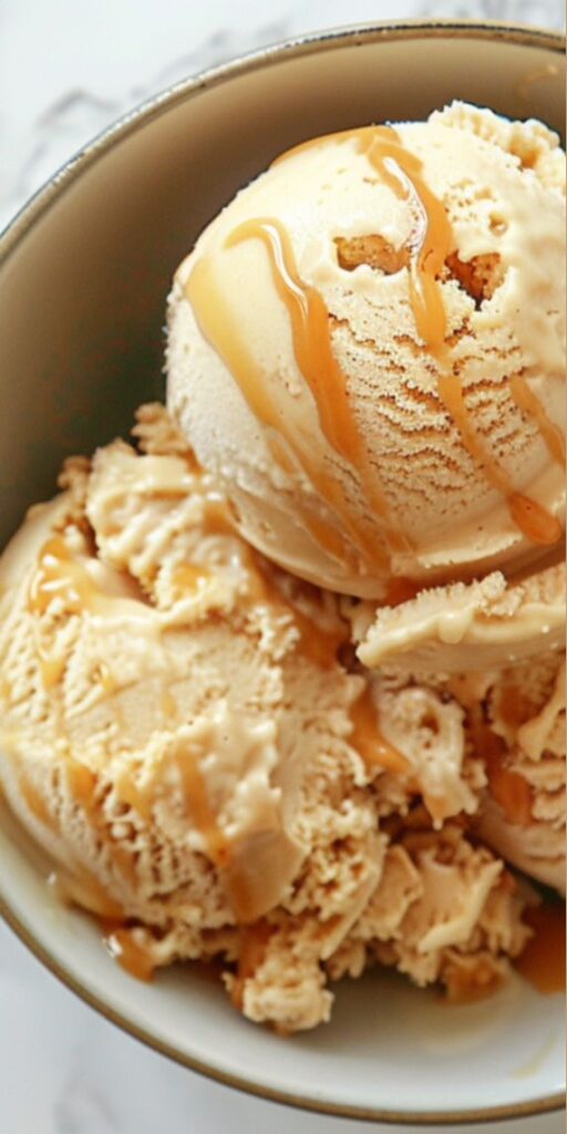 Creamy caramel ice cream in a bowl, topped with drizzle, offering a delicious frozen dessert treat.