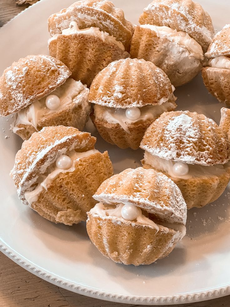 Delicious cream-filled pastries topped with powdered sugar and decorative pearls on a white plate.