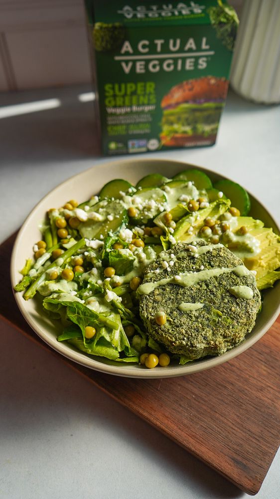 Green veggie burger salad with peas and creamy dressing, featuring Actual Veggies packaging in the background.