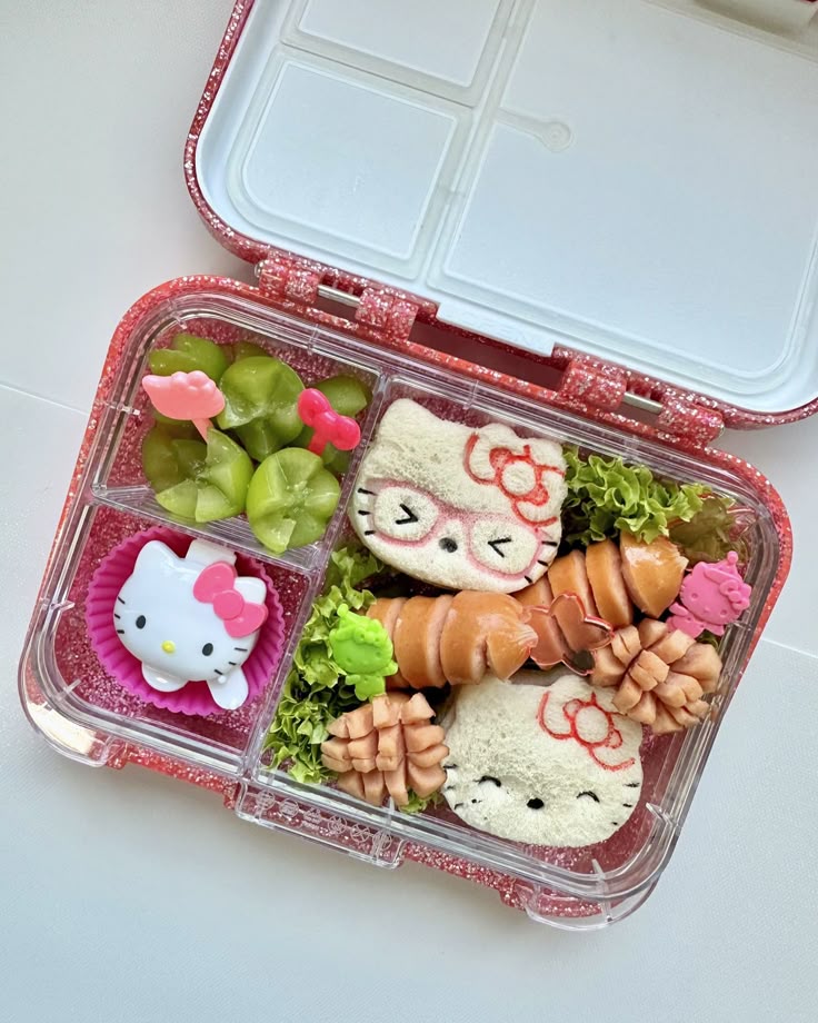 Cute Hello Kitty-themed bento box with sandwiches, sausages, and fruit arranged in an adorable and appetizing way.