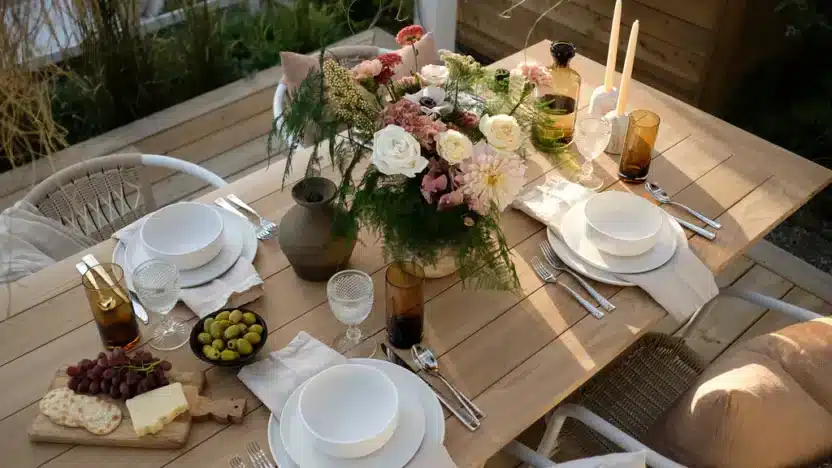 Elegant outdoor dining table with floral centerpiece, plates, cutlery, and glasses set for four.