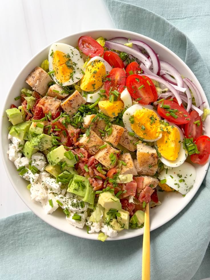Colorful Cobb salad with eggs, avocado, chicken, bacon, and tomatoes on a white plate. Fresh and delicious.