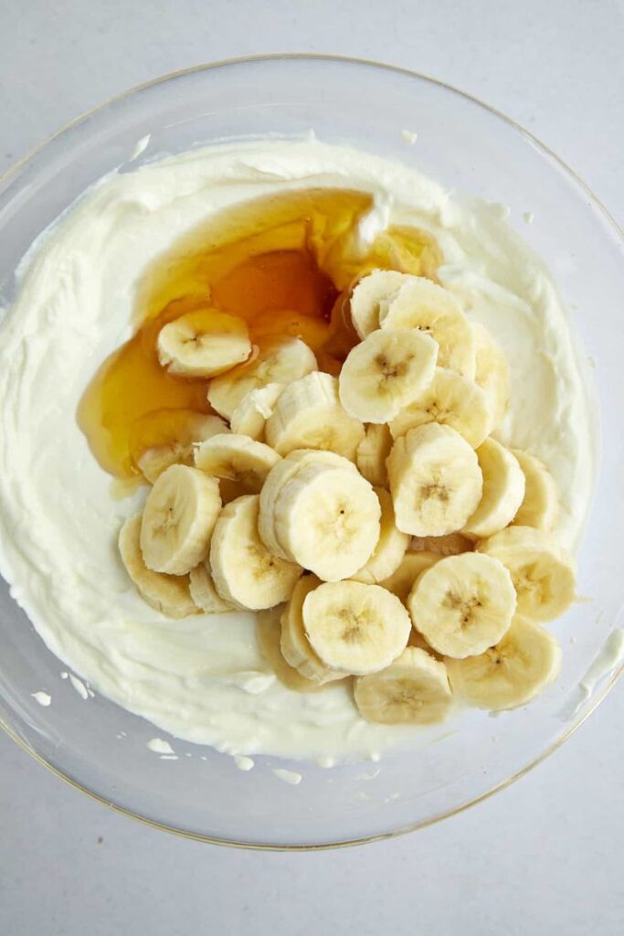 Bowl of sliced bananas with creamy yogurt and honey, perfect for a healthy breakfast or dessert topping.