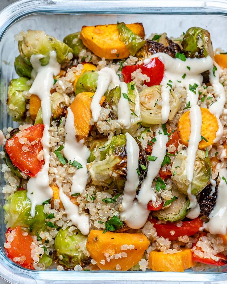 Healthy quinoa salad with roasted vegetables and creamy dressing in a glass container. Perfect for a nutritious lunch.