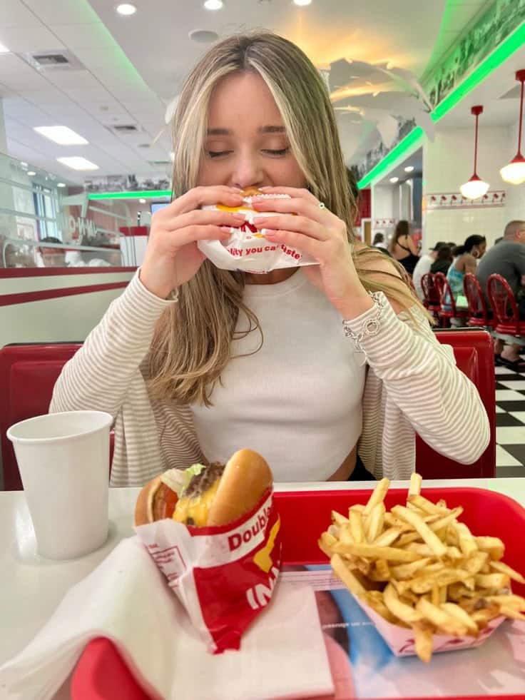 Person enjoying a burger and fries at a retro-style diner.
