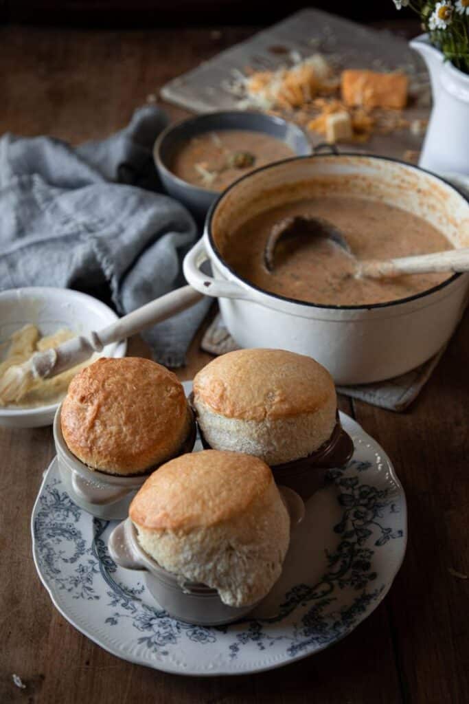 Freshly baked bread bowls with creamy soup served on a rustic table setting.