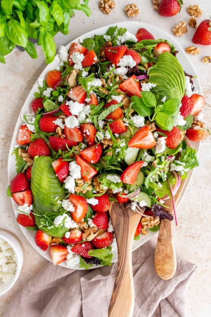 Fresh summer salad with strawberries, avocado, and feta on a platter. Perfect for a healthy, colorful meal.