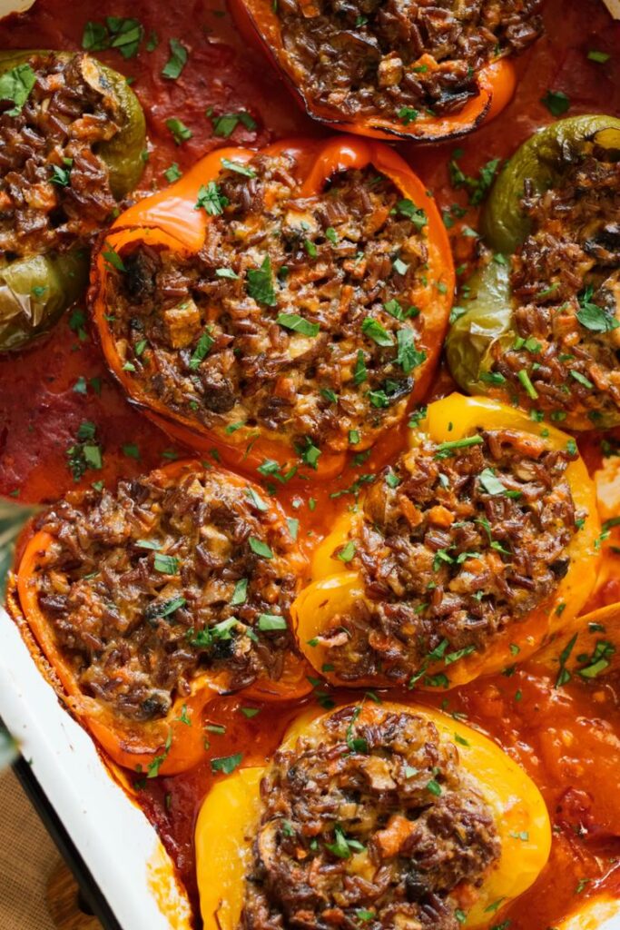 Close-up of colorful stuffed bell peppers with rice and herbs in a tomato sauce.
