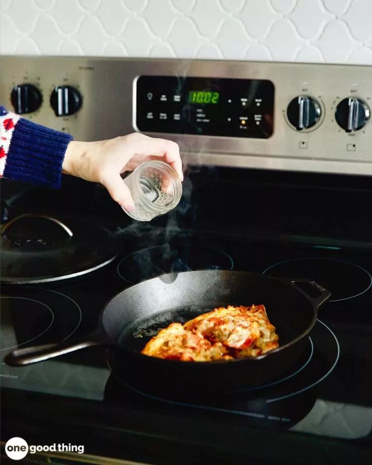 Adding water to a cast iron skillet while cooking on a stovetop for a delicious meal at 11:00 AM.