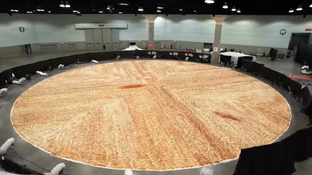 World's largest pizza displayed in a spacious hall, showcasing its massive size and texture.