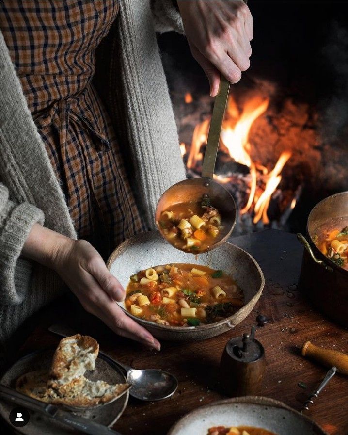 Hearty vegetable soup served by a cozy fireside, a perfect winter comfort meal.