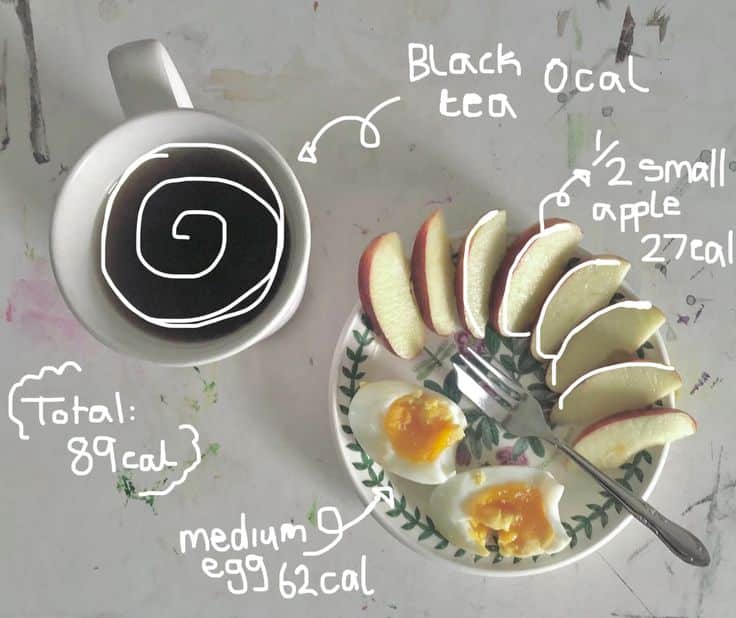 Healthy breakfast with black tea, apple slices, and boiled egg on a plate, totaling 89 calories.