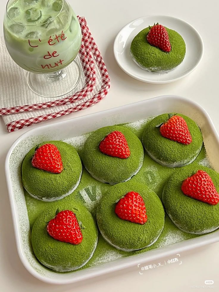 Matcha mochi with strawberries on top, paired with iced green tea, on a checkered cloth.
