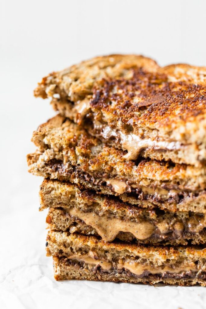 Stacked grilled almond butter and chocolate sandwiches on rustic bread. Perfect for a delicious snack or breakfast.