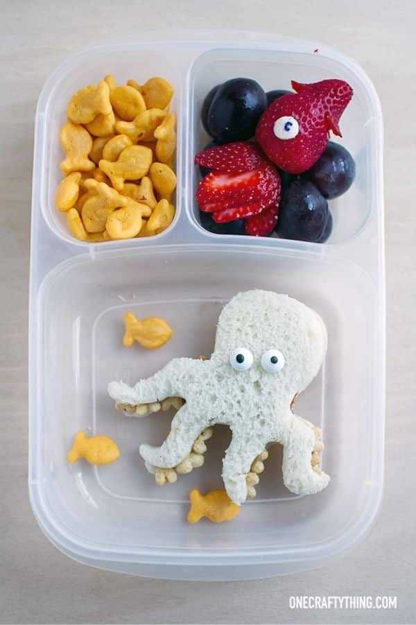 Creative kids lunchbox with octopus sandwich, fish crackers, and berry sea creature. Fun and healthy meal idea.