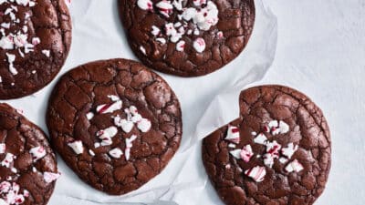 Chocolate cookies topped with crushed peppermint on parchment paper. Ideal holiday treat for festive occasions.