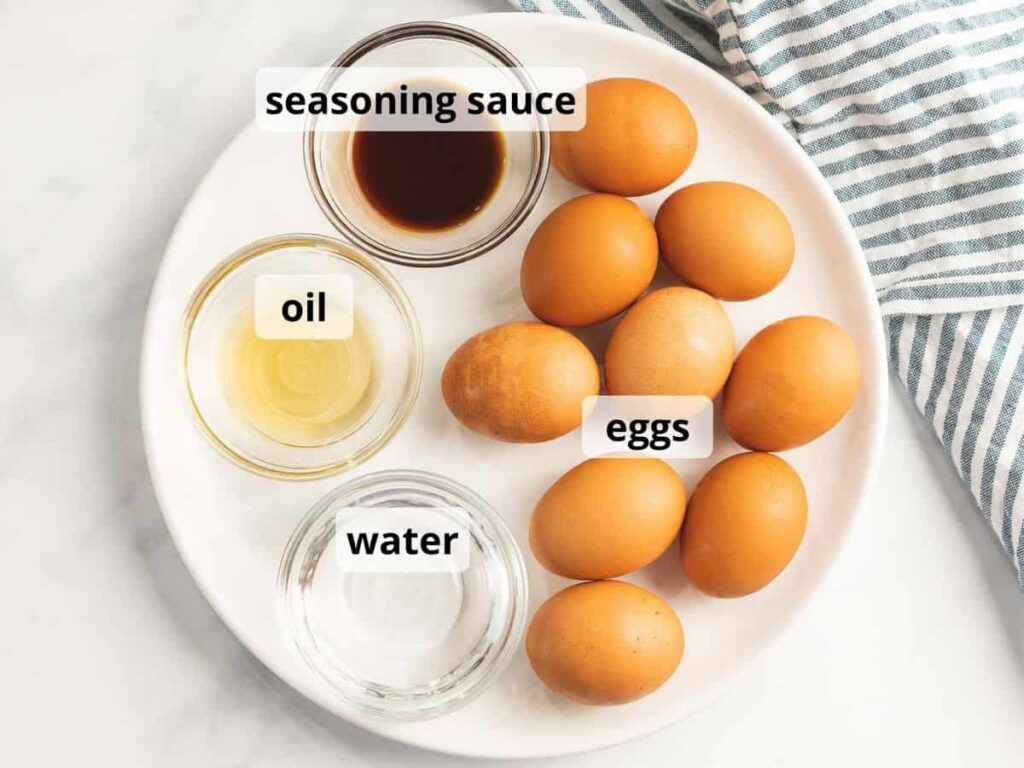 Plate with labeled eggs, seasoning sauce, oil, and water arranged on a white table with a striped cloth.