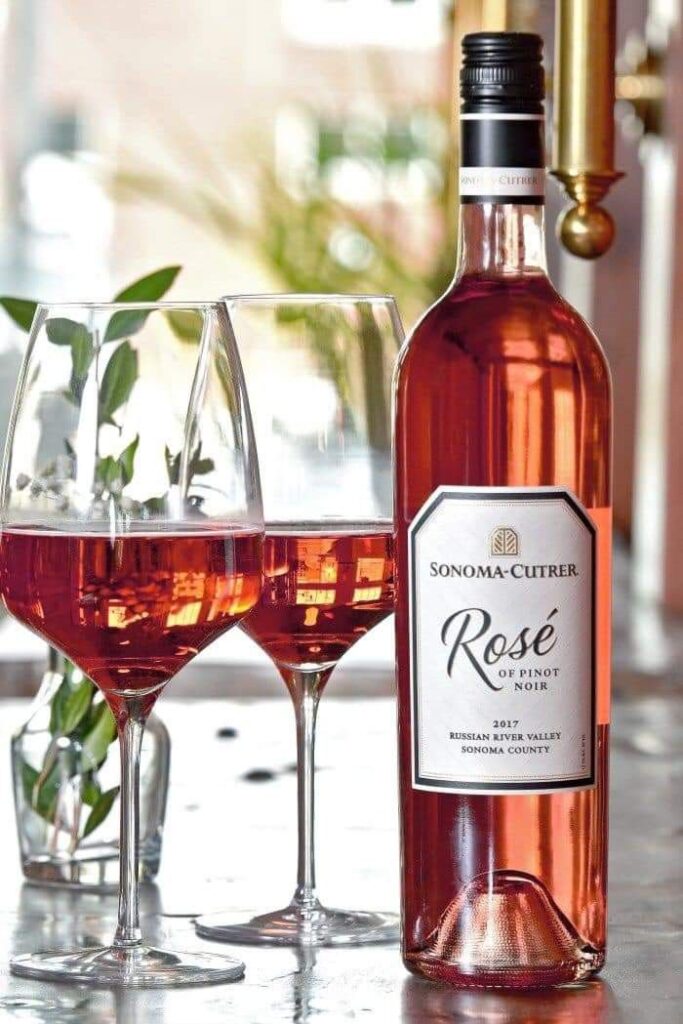 Bottle and glasses of Sonoma-Cutrer Rosé wine on a table, bright and inviting atmosphere.