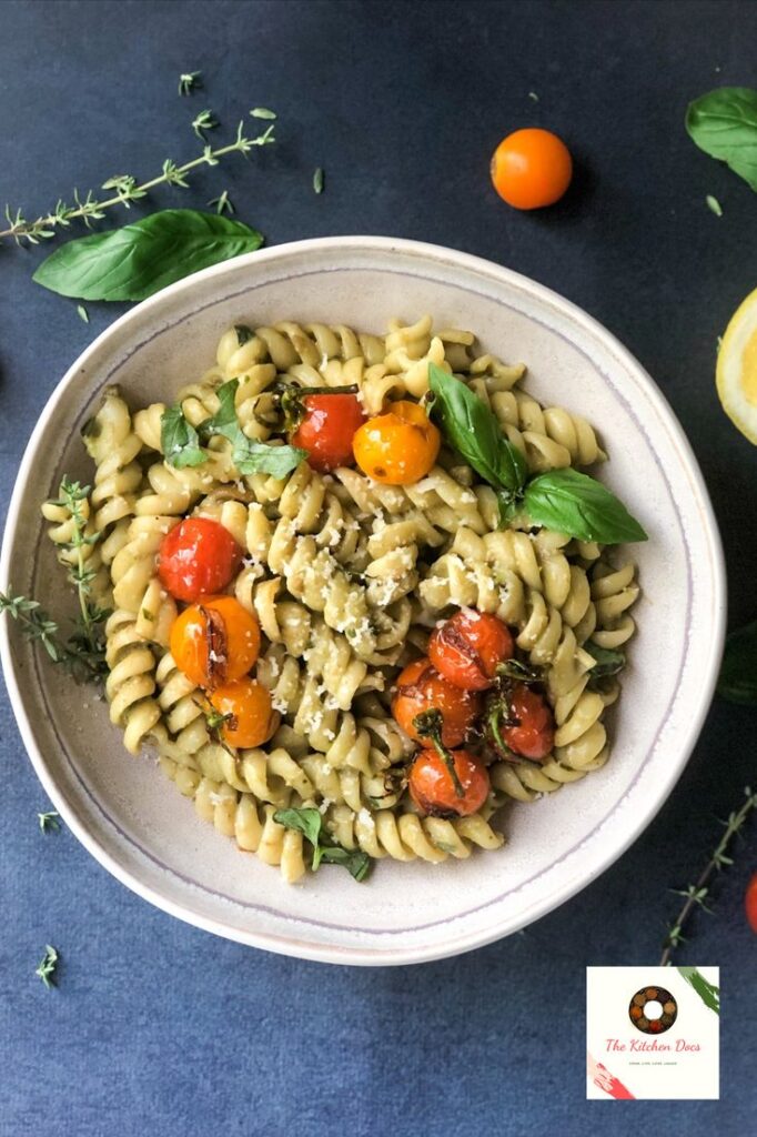 Pasta dish with fusilli, roasted cherry tomatoes, and fresh basil in a white bowl, garnished with parmesan.