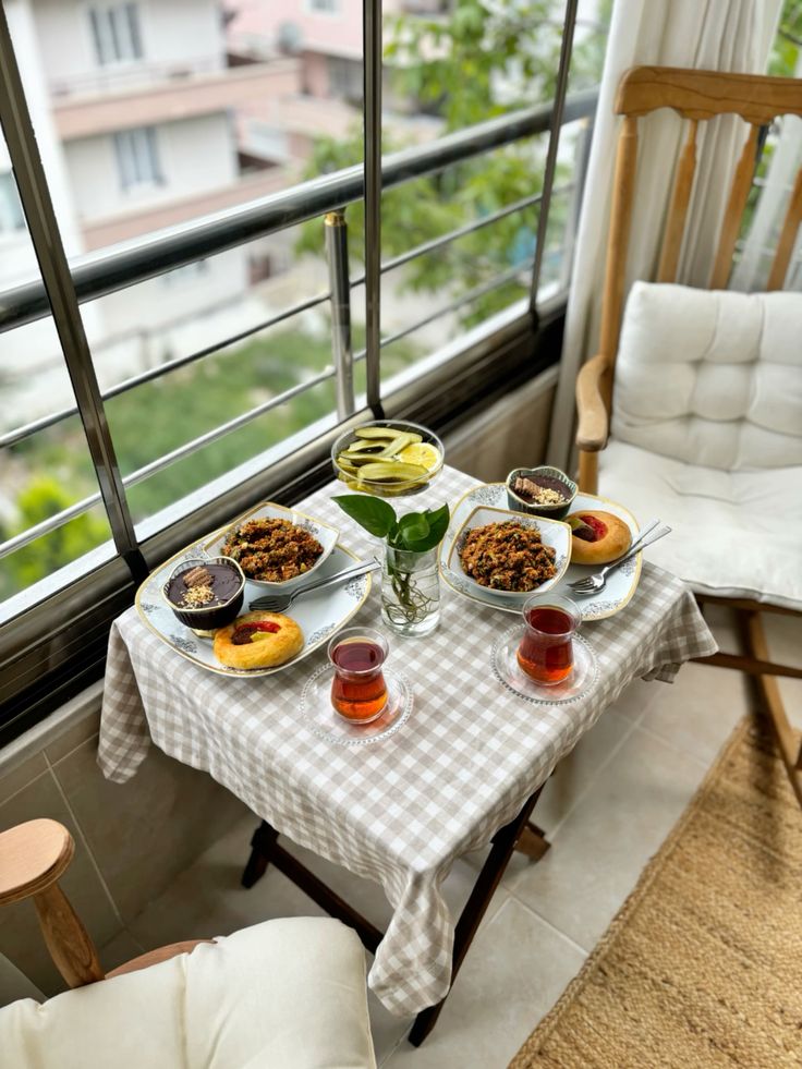 Cozy balcony breakfast setup with hearty meals, tea, and a scenic view, perfect for a relaxing morning.