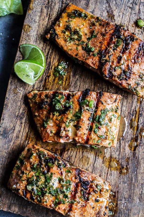 Grilled salmon with herbs and lime on a wooden board.