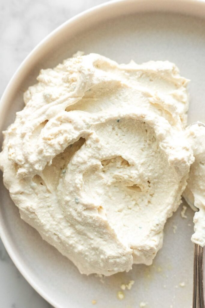 Creamy ricotta cheese spread on a white plate, perfect for baking or cooking dishes.
