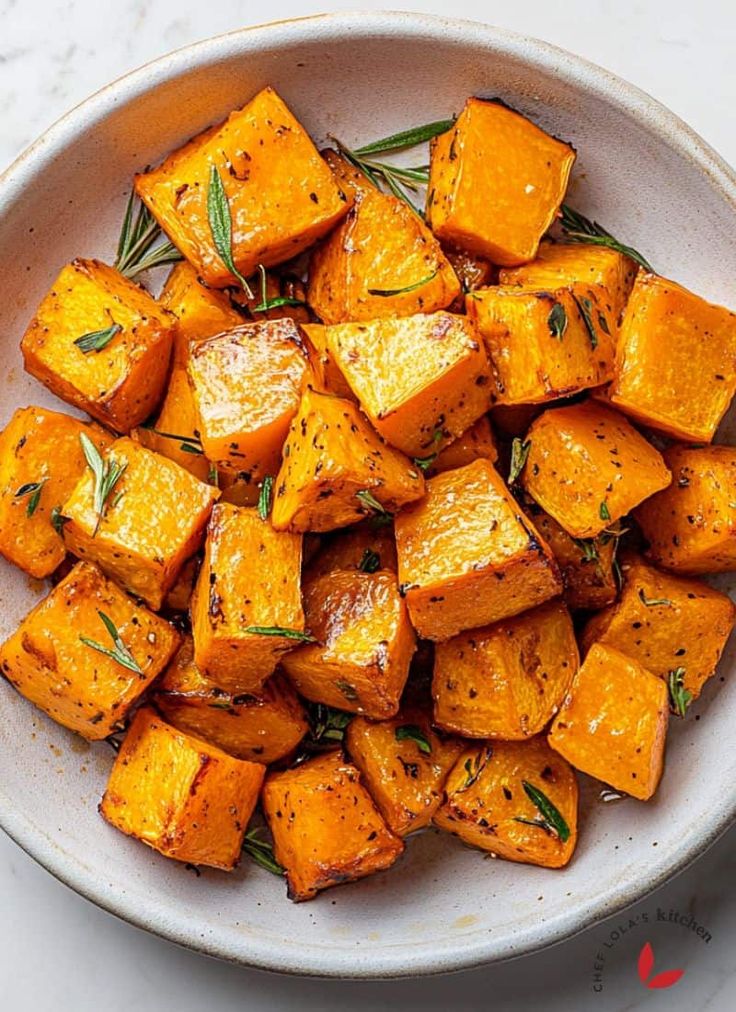 Roasted butternut squash cubes with herbs in a white bowl, perfect for a delicious and healthy side dish.