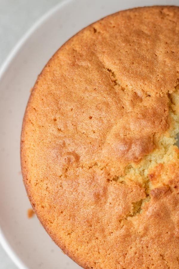 Golden sponge cake on a white plate, top view, highlighting a delicious homemade dessert.
